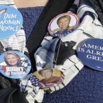 Una mujer muestra las chapas que lleva de su candidata, Hillary Clinton