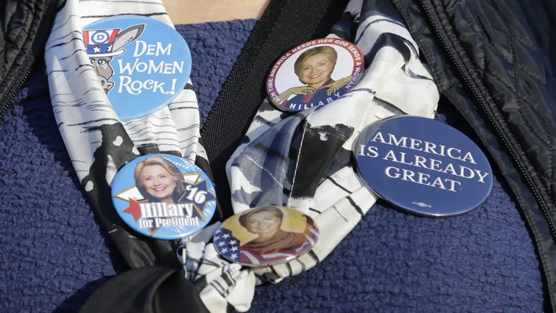 Una mujer muestra las chapas que lleva de su candidata, Hillary Clinton