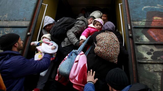 Los refugiados se apresuran a subir a un tren antes de su salida hacia Serbia