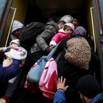 Los refugiados se apresuran a subir a un tren antes de su salida hacia Serbia