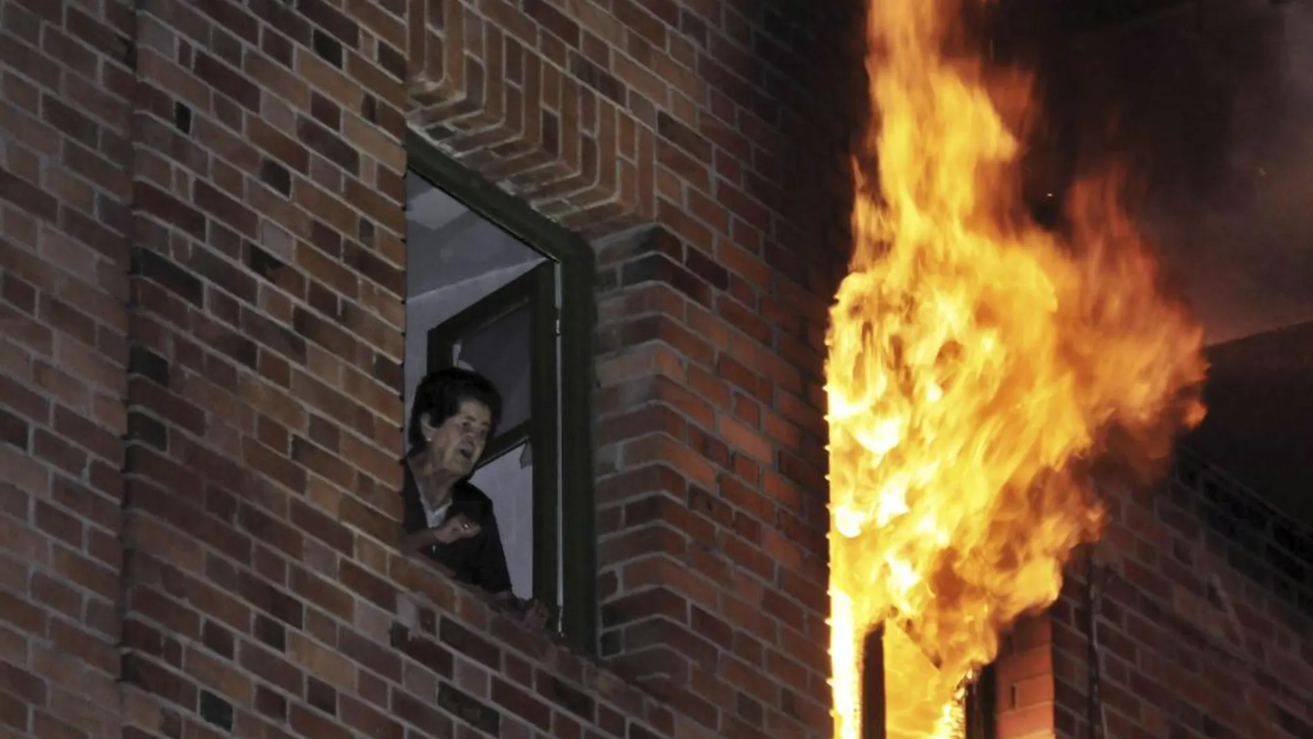 Una mujer junto a la ventana en llamas tras la explosión