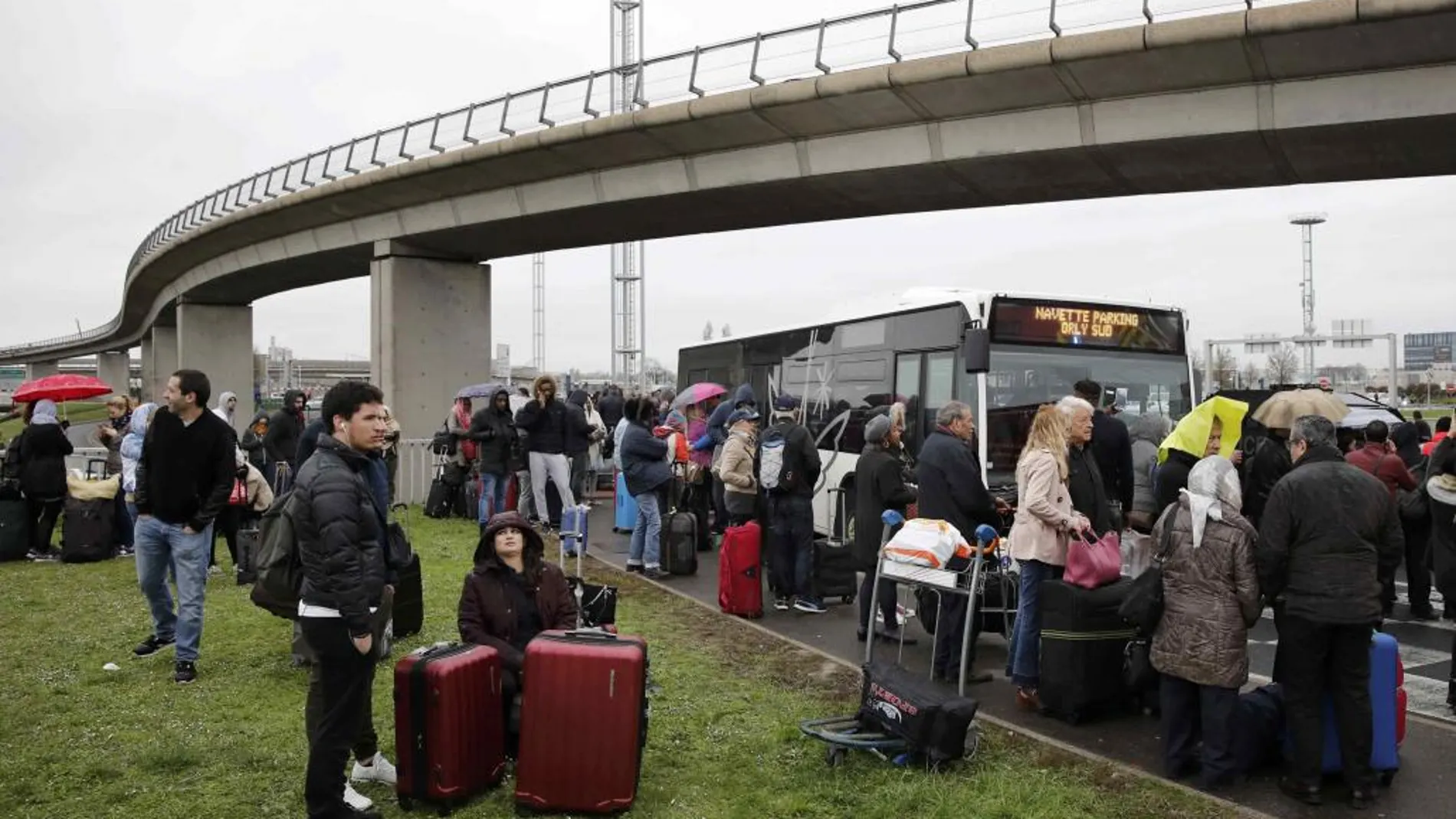 Los pasajeros esperan junto a la terminal para ser trasladados.