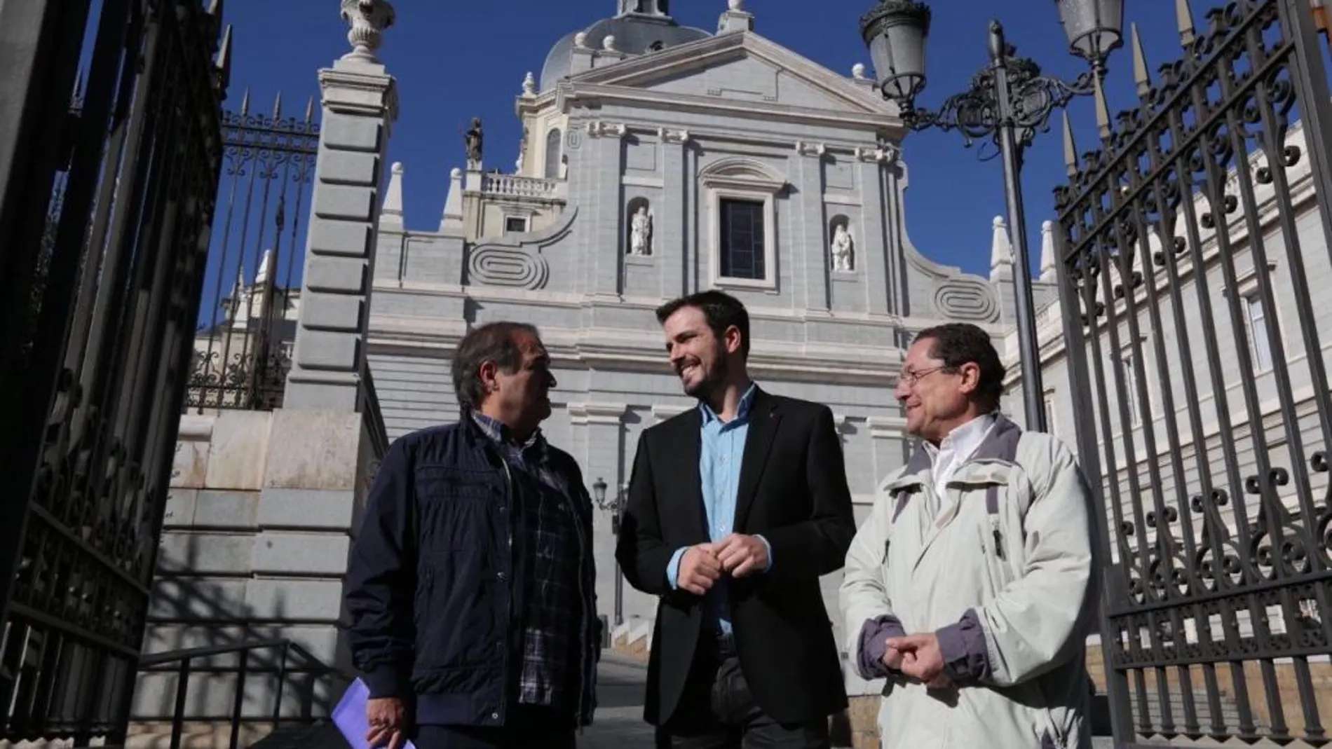 En el centro, Alberto Garzón esta mañana ante la Catedral de la Almudena, en Madrid; a la izquierda, Francisco Delgado, presidente de Europa Laica.