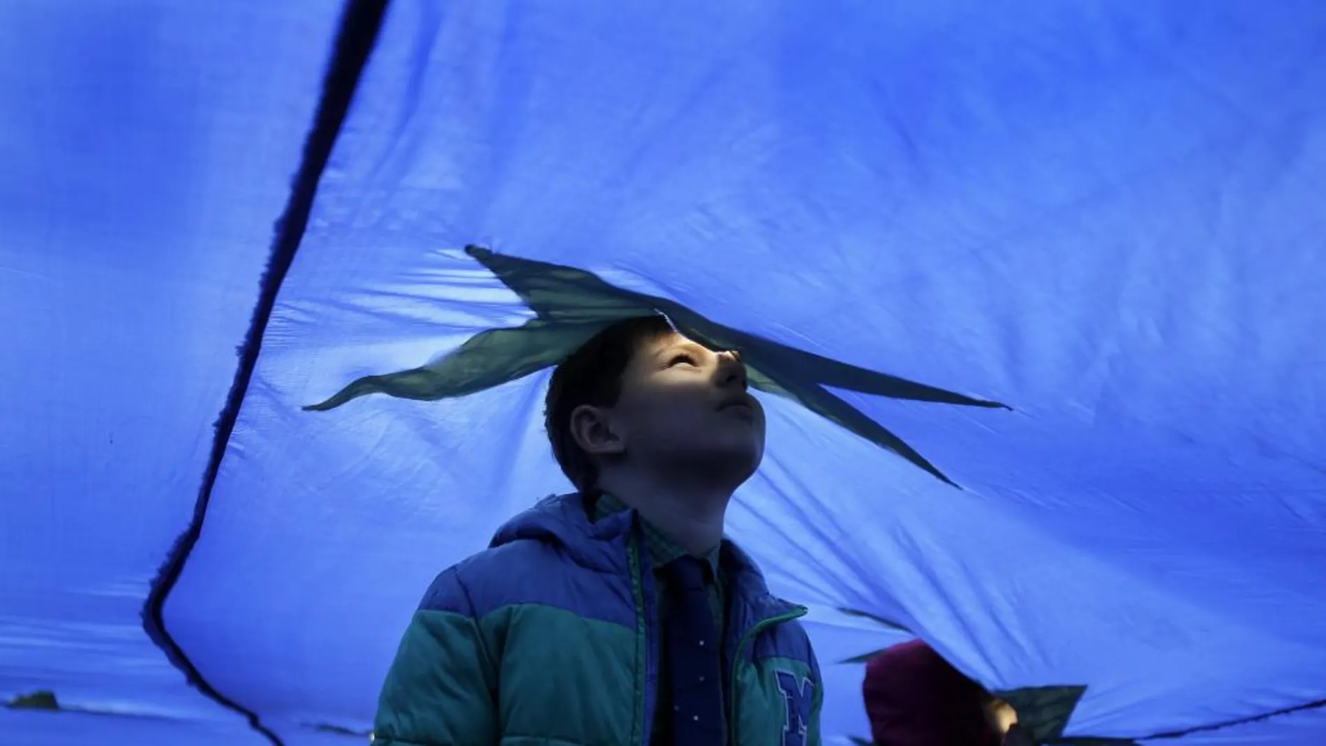 Fotografía de archivo de un niño asomado por el agujero de ventilación de una bandera gigante de la Unión Europea (UE)