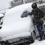 Una persona trata de limpiar su coche de la nieve caída en la localidad de Lecumberri