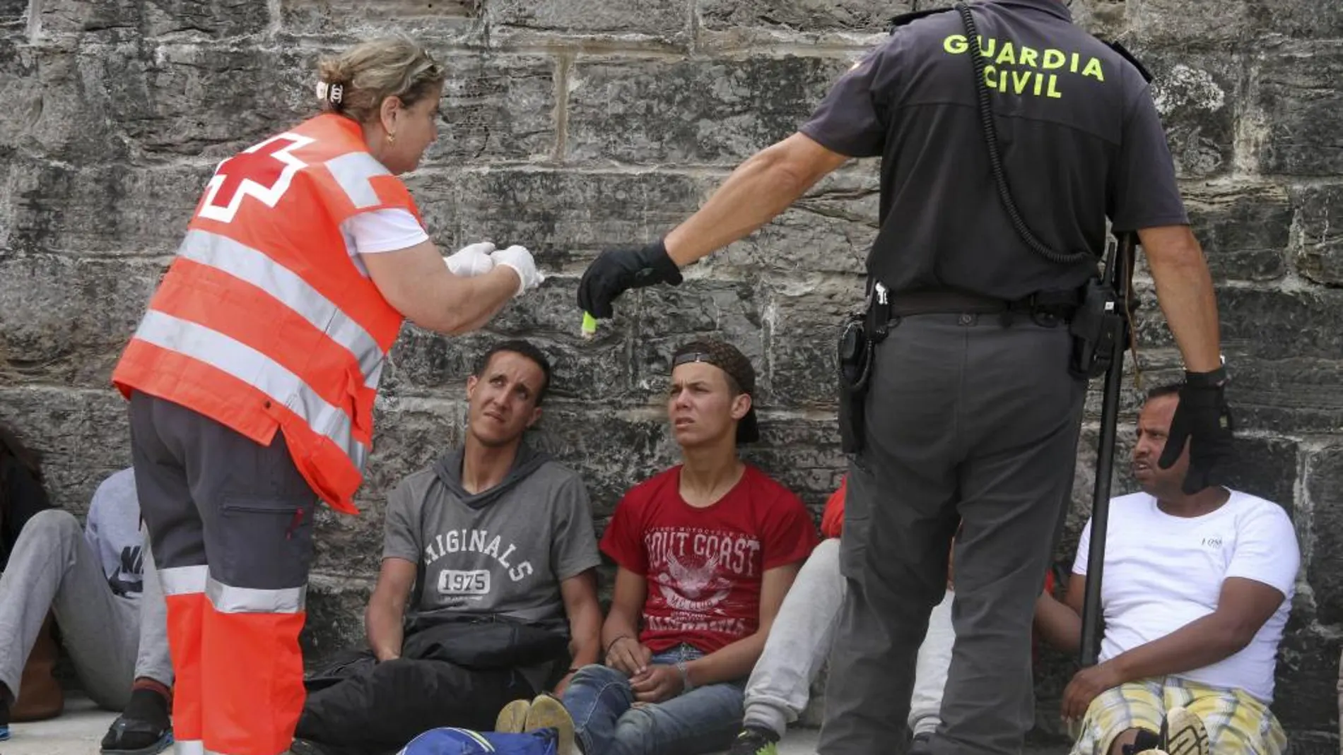 Agentes de la Guardia Civil y personal de Cruz Roja ayudan, a su llegada al puerto de Tarifa (Cádiz), a los 88 inmigrantes de origen subsahariano rescatados en la mañana del viernes