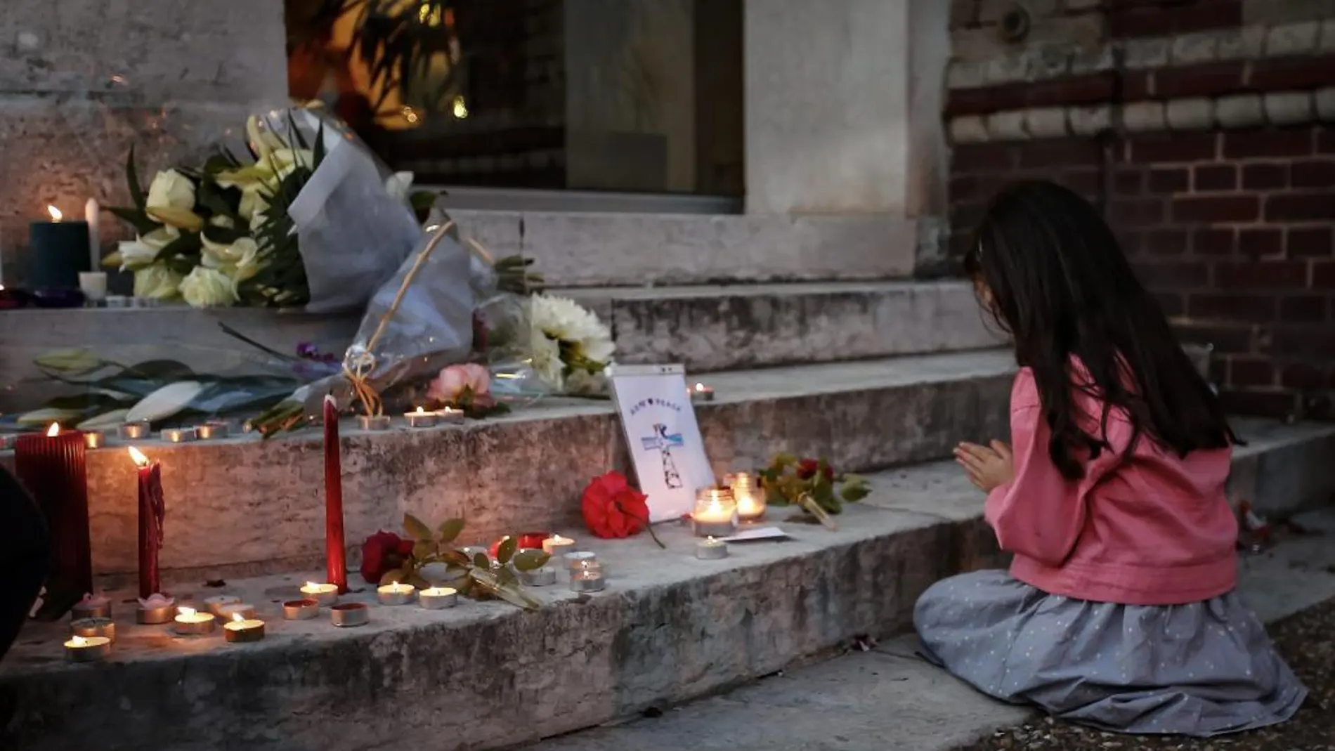 Una niña ora junto a un memorial por el sacerdote asesinado el pasado 26 de julio en una iglesia de Normandía