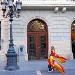 Dos niños pasean por el ayuntamiento de Sabadell con sendas banderas españolas, ayer, mientras dos personas cuelgan la misma insignia en una ventana