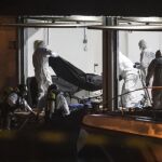 Bomberos y agentes de la Guardia Civil trasladan los cuerpos de los 5 inmigrantes fallecidos