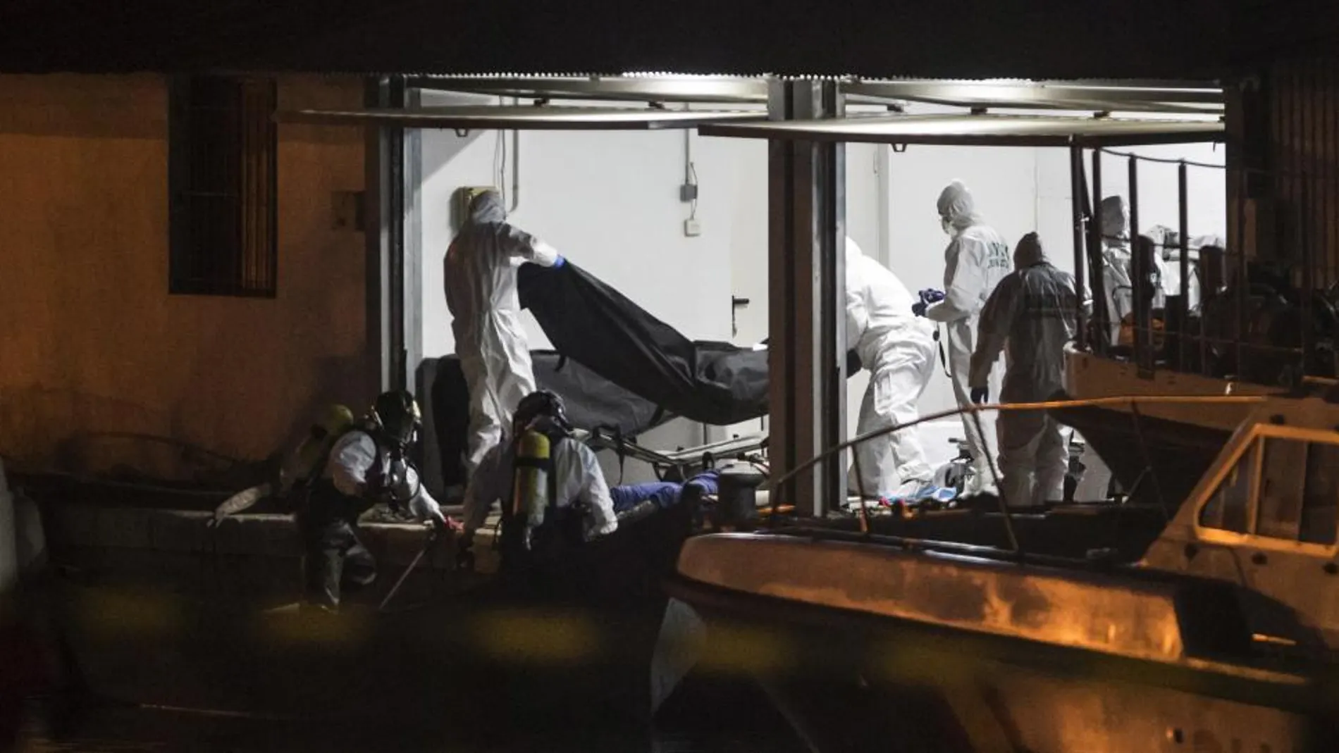 Bomberos y agentes de la Guardia Civil trasladan los cuerpos de los 5 inmigrantes fallecidos