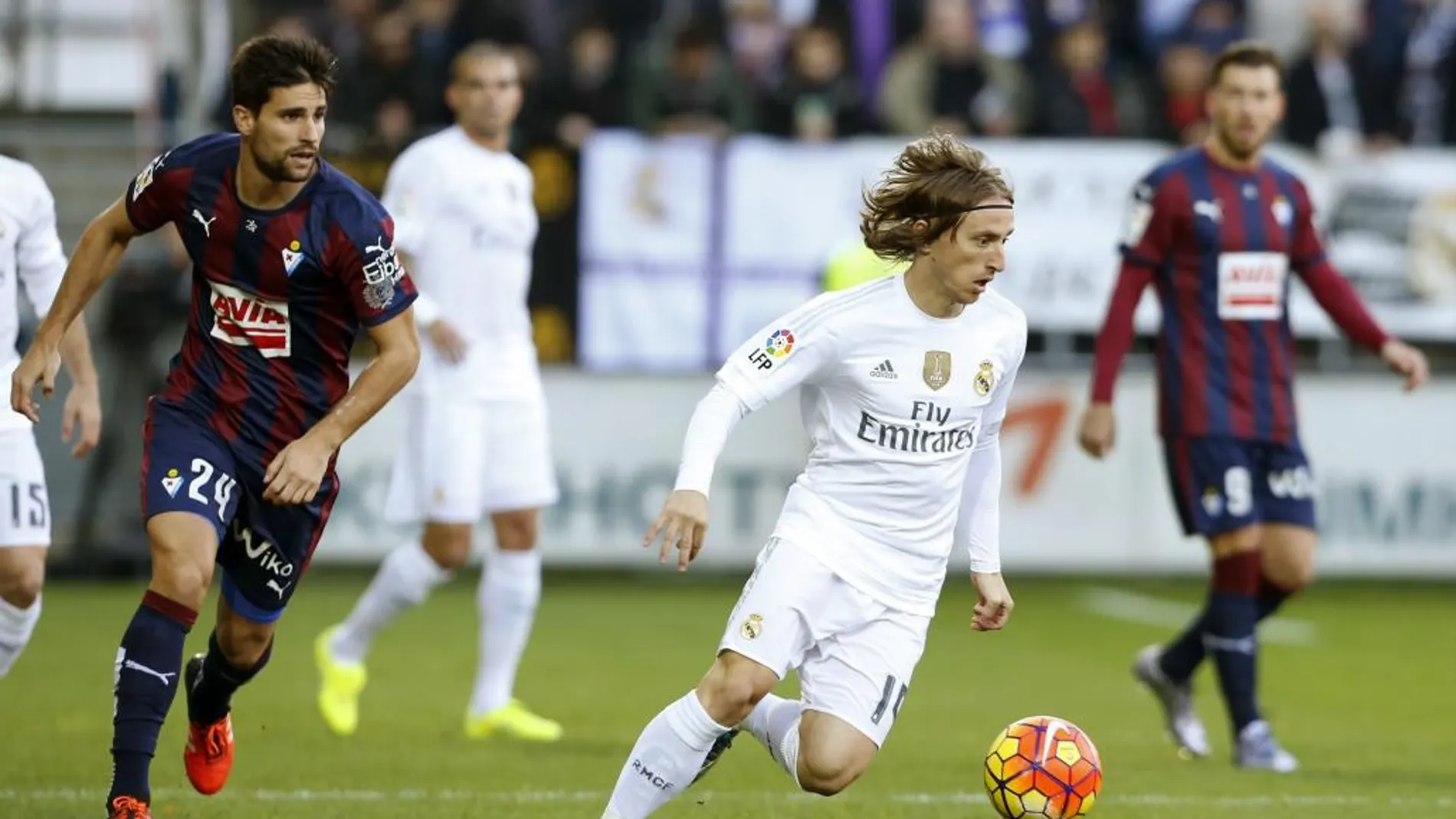 Luka Modric seguido por el centrocampista del Eibar Adrián González.