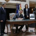 El Rey Felipe VI, junto a la Reina Letizia y el embajador de Francia en España, Yves Saint-Geours (i), firma en el libro de condolencias instalado en el vestíbulo de la residencia del embajador francés en Madrid por los atentados terroristas de ayer en París.