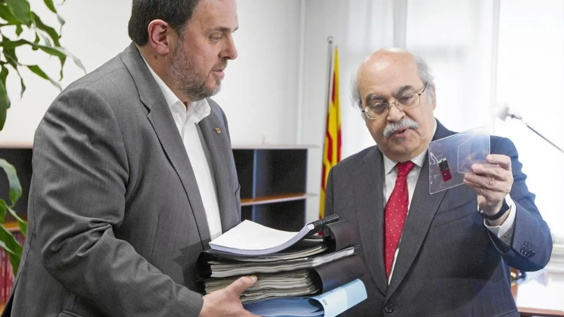 El nuevo conseller de Economía y vicepresidente de la Generalitat, Oriol Junqueras, recibe de su antecesor en el cargo, Andreu Mas-Colell documentación del departamento