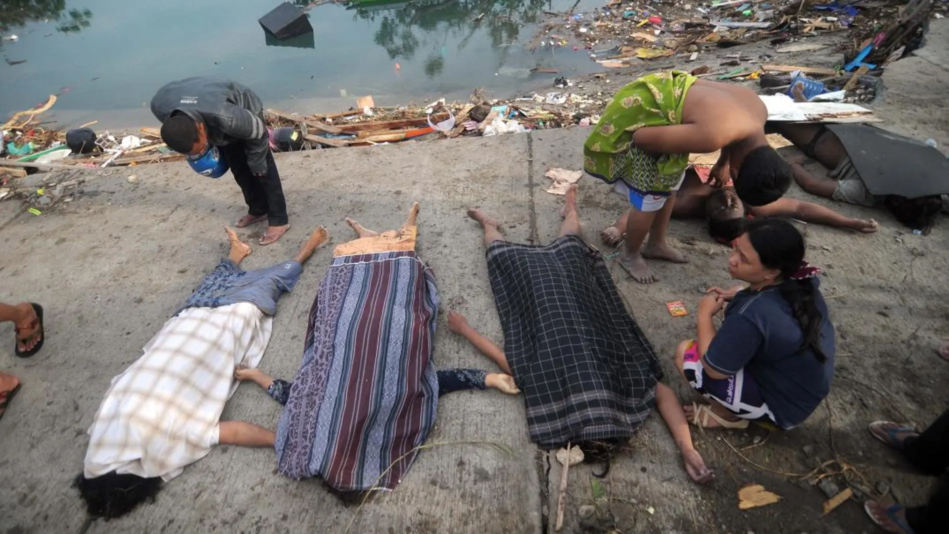 Supervivientes permanecen junto a las víctimas en el tsunami en Palu (Indonesia). Efe