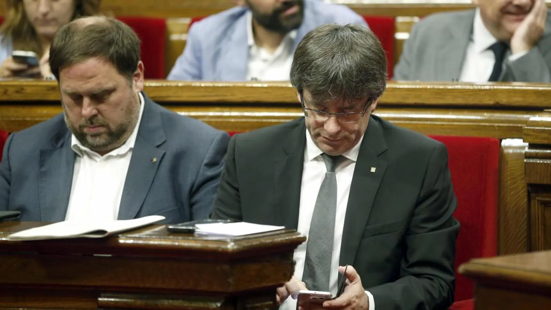 El presidente de la Generalitat, Carles Puigdemont (d), y su vicepresidente, Oriol Junqueras, durante el pleno del Parlament