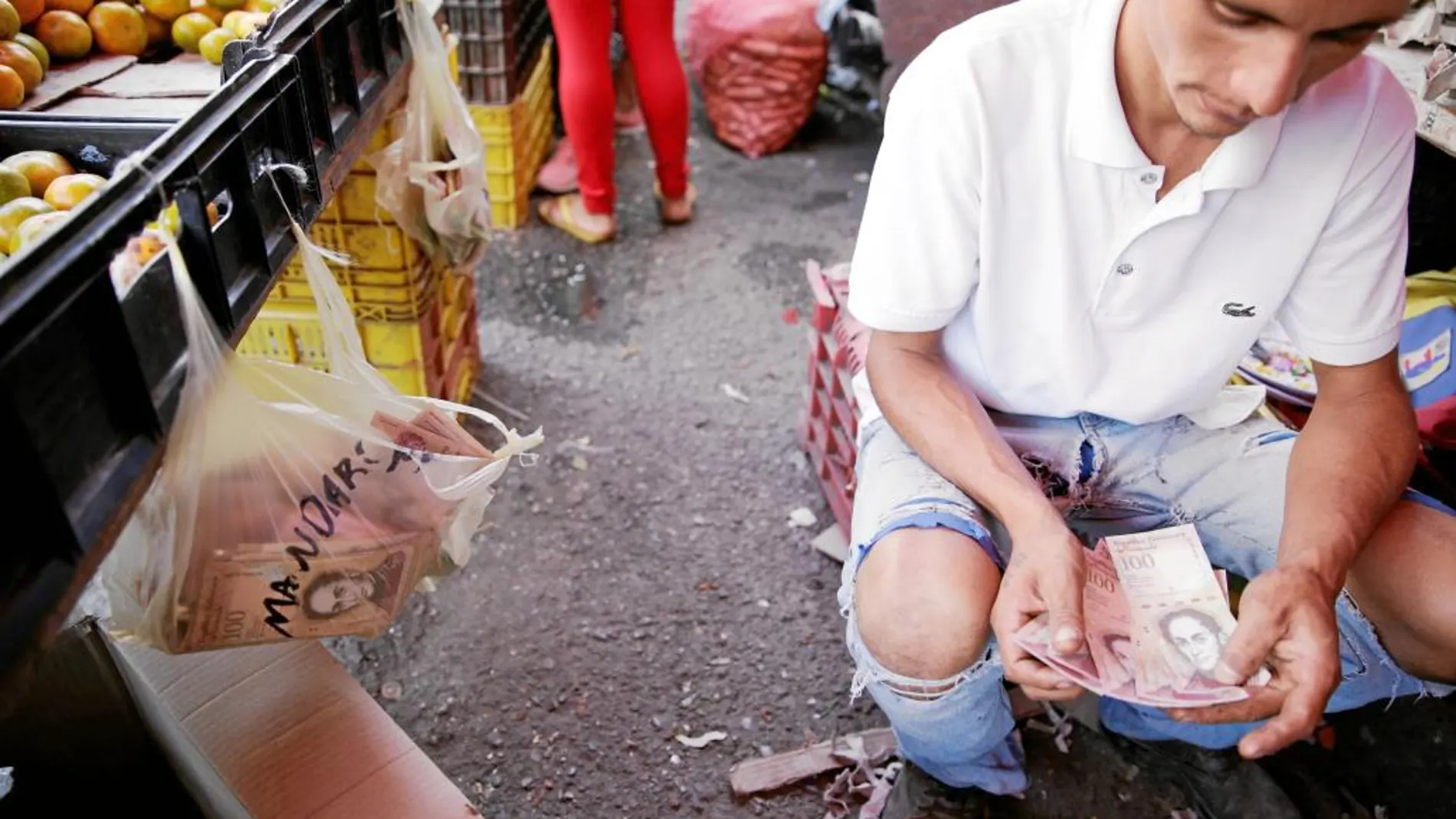 Un vendedor cuenta un fajo de billetes en un mercado en el barrio de Petare en Caracas, ayer