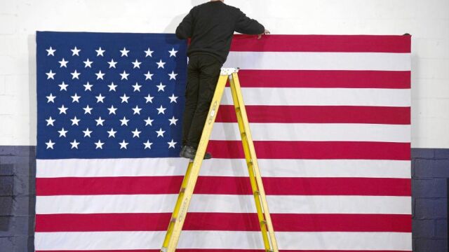 Un trabajador coloca una bandera en la Universidad de Hooksett antes de un acto de Hillary Clinton