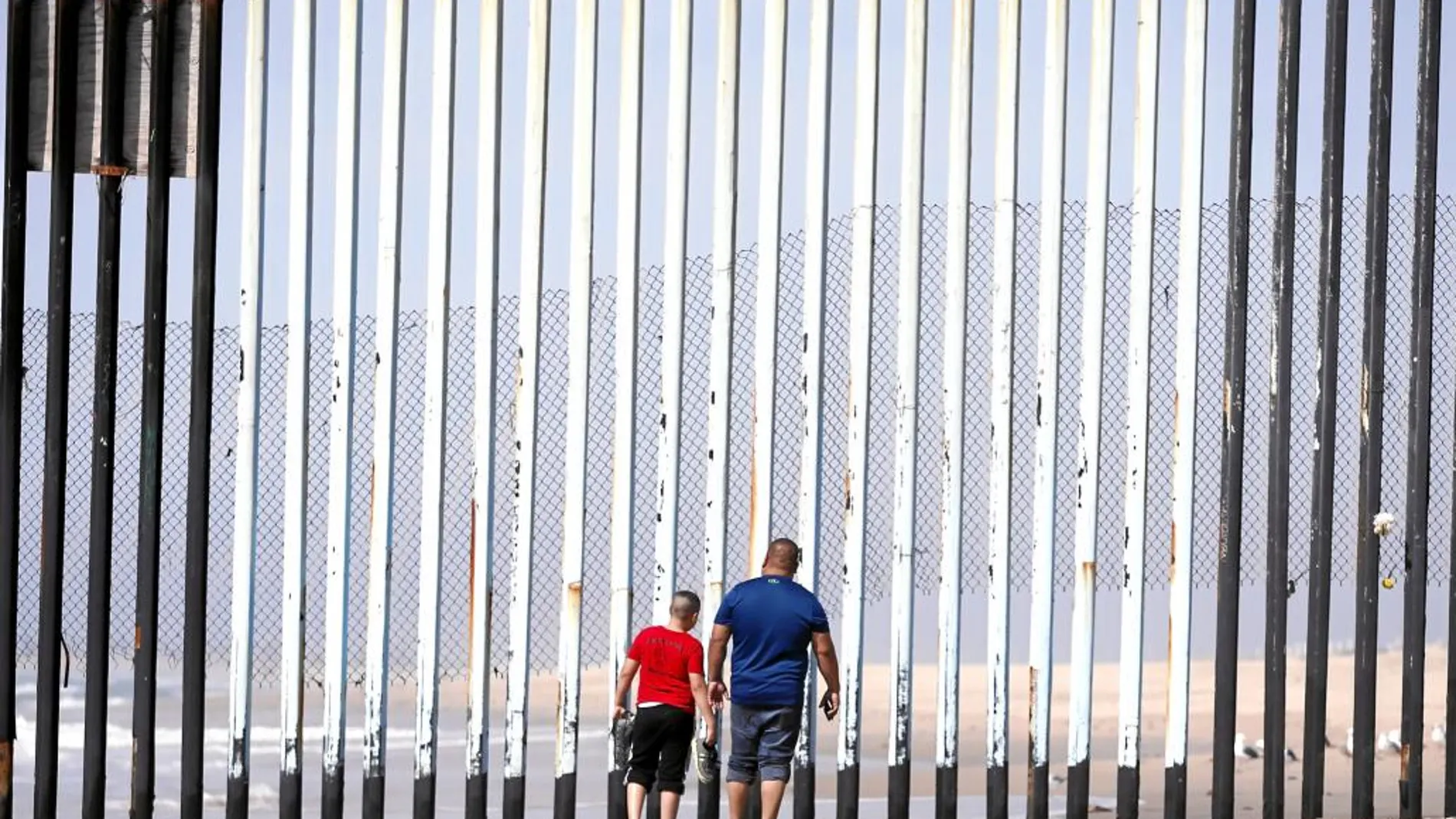 Dos mexicanos caminan hacia la frontera con Estados Unidos en la ciudad de Tijuana