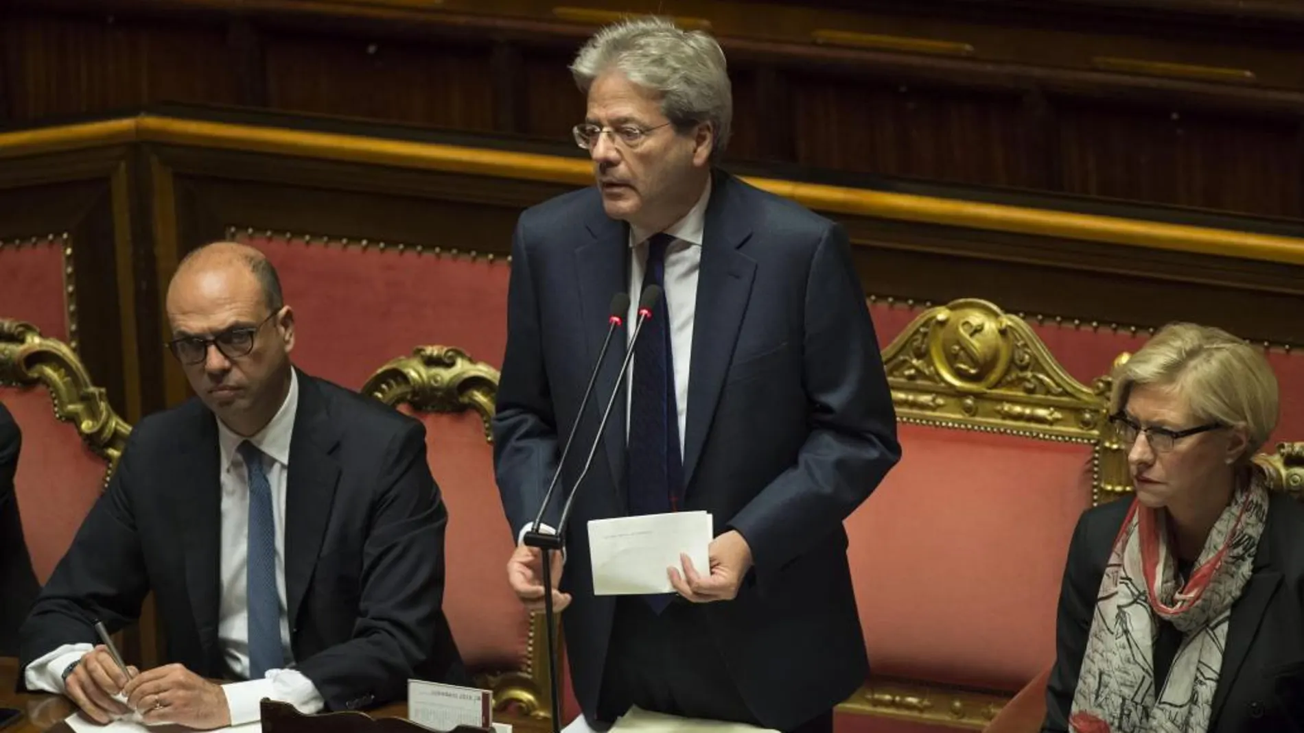 El primer ministro italiano, Paolo Gentiloni (c), toma la palabra en presencia del ministro de Asuntos Exteriores, Angelino Alfano (d), y de la ministra de Defensa, Roberta Pinotti (d), en el Senado en Roma, Italia, hoy, 14 de diciembre de 2016