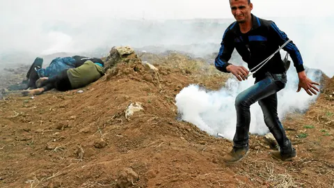 40.000 manifestantes. Un palestino con una onda corre mientras otros buscan refugio en el primer aniversario de la Gran Marcha del Retorno, ayer en el este, frente al muro fronterizo