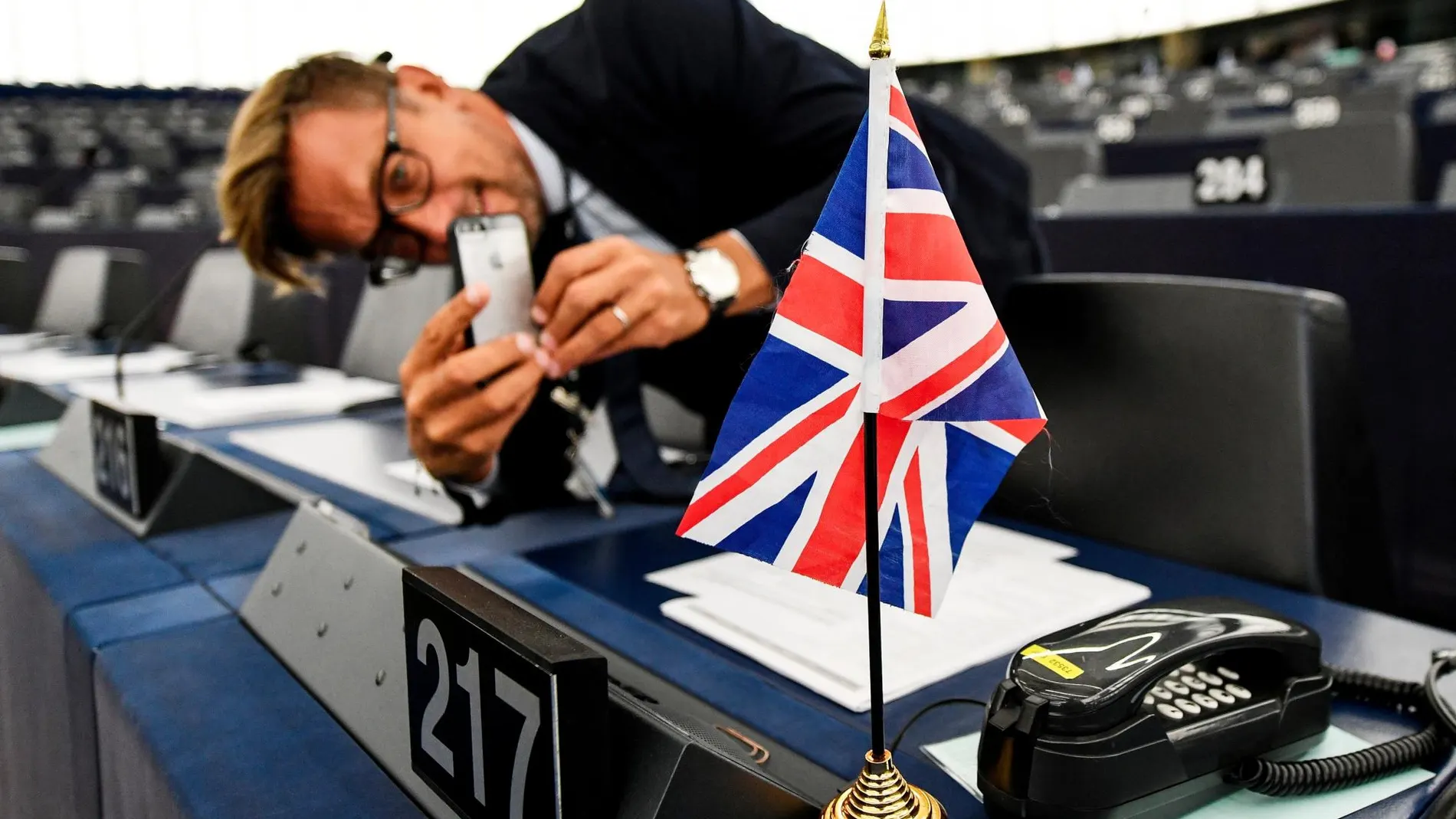 Un hombre fotografía una bandera del Reino Unido antes del comienzo de una sesión en el Parlamento Europeo en Estrasburgo