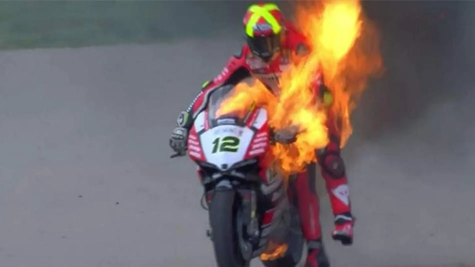 Xavi Forés sujetando su moto en llamas
