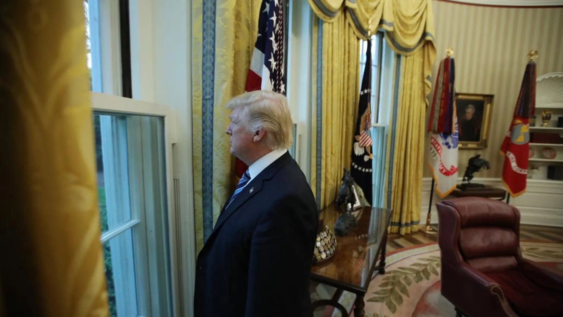 Donald Trump mira por una ventana del despacho oval