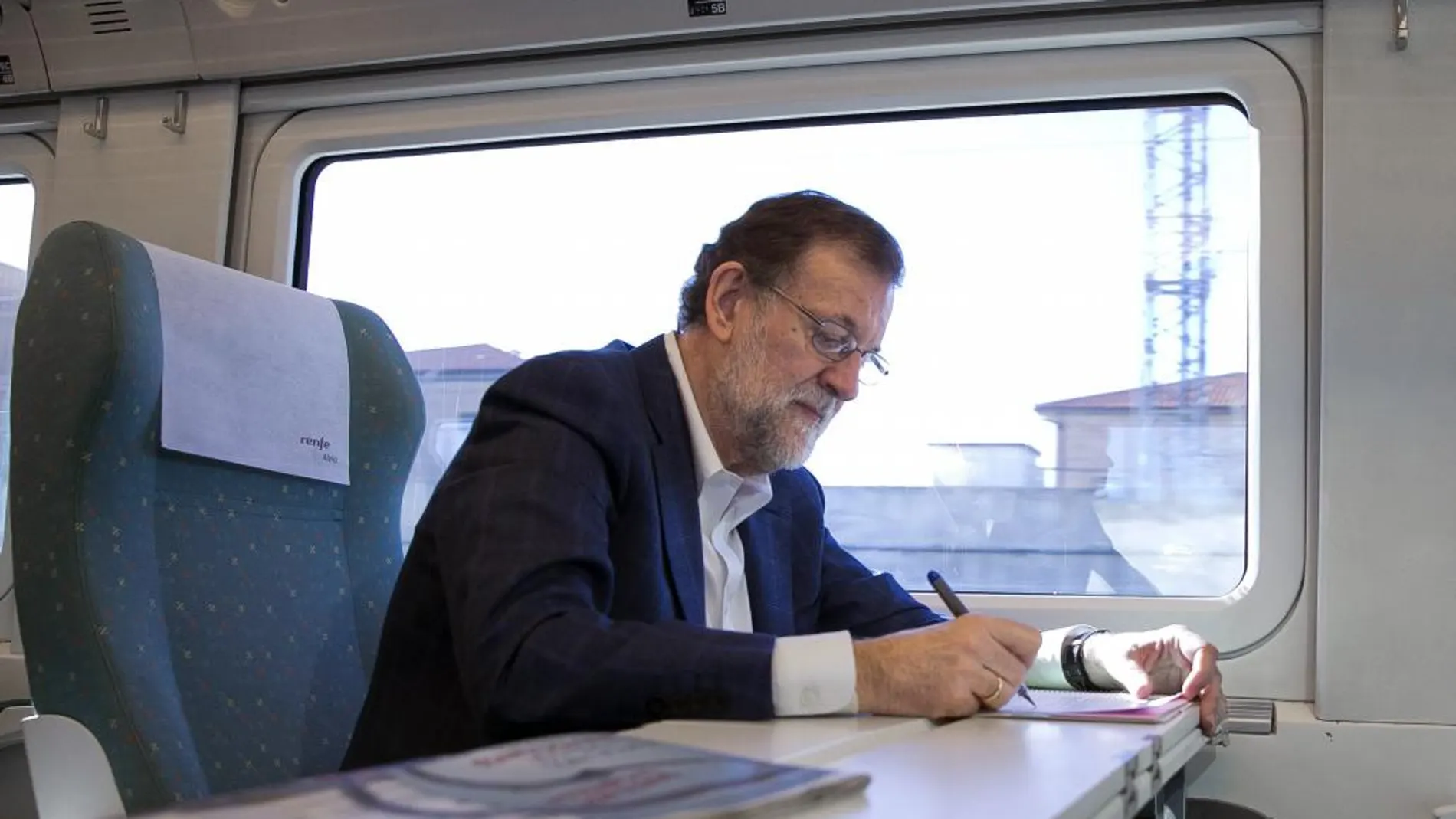 El presidente del Partido Popular y presidente en funciones del Gobierno, Mariano Rajoy, tomando notas en el tren en el que viaja hacia Zamora
