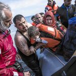 Un emigrante sirio sostiene a su hijo a la llegada ayer a la isla griega de Lesbos procedente de Turquía