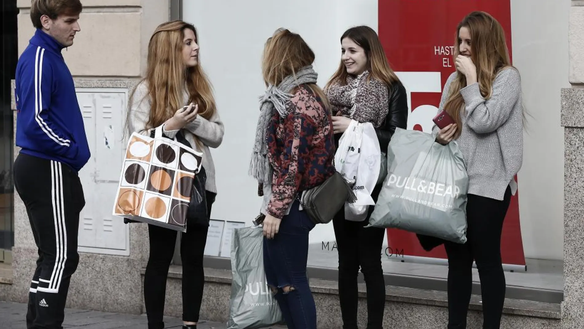 Un grupo de jóvenes, en el exterior de un comencio del centro de Pamplona donde las rebajas de invierno han comenzado.