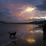 Un hombre pasea al amanecer en la playa de Ondarreta de San Sebastiá