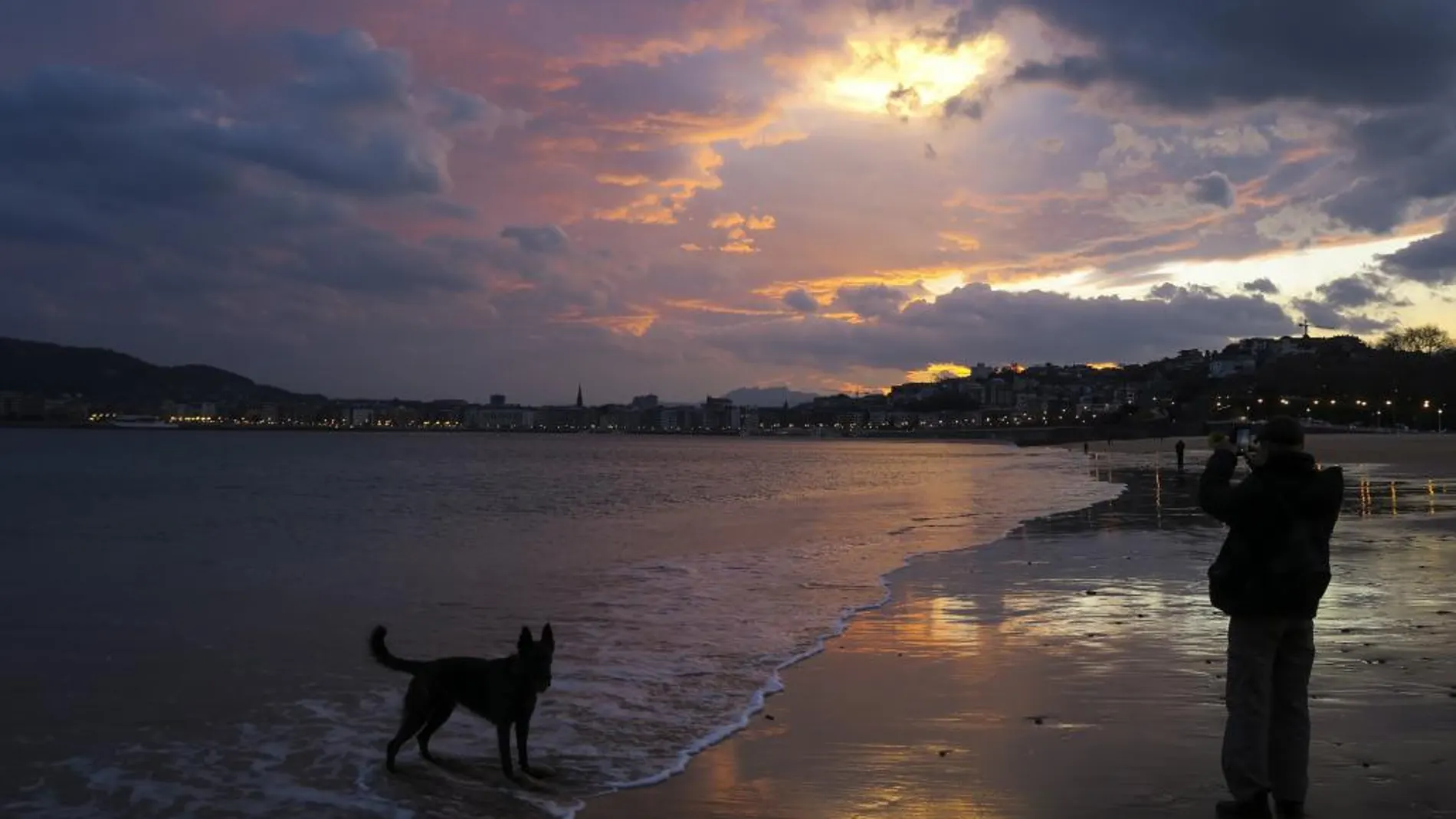 Un hombre pasea al amanecer en la playa de Ondarreta de San Sebastiá