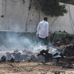 Un hombre pasa junto a los restos de uno de los coches bomba