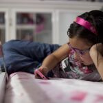 Una niña consulta el móvil en su habitación