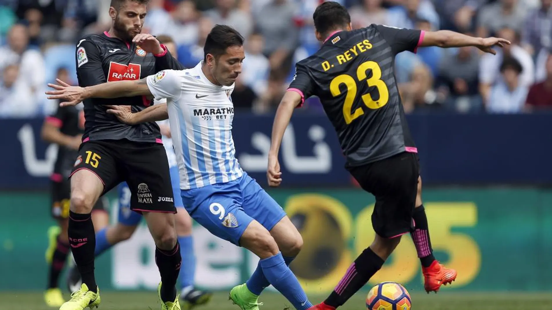 El delantero del Málaga Charles Dias (c) disputa un balón ante los jugadores del Espanyol David López (i) y Diego Reyes hoy en el estadio de La Rosaleda.