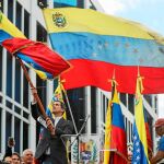 Juan Guaidó ondea una bandera venezolana ayer en Caracas tras anunciar que asumía las competencias de la presidencia