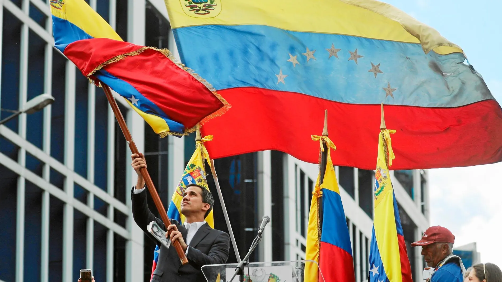 Juan Guaidó ondea una bandera venezolana ayer en Caracas tras anunciar que asumía las competencias de la presidencia