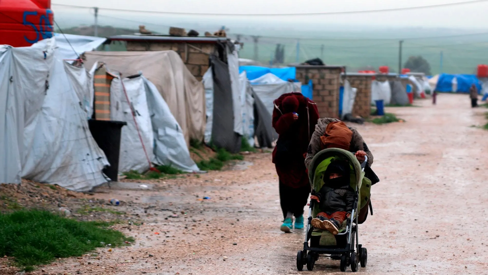 Imagen de dos mujeres con un niño en el campamento de Roj
