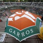 Un espectador protegiéndose con un paraguas de la lluvia en Roland Garros