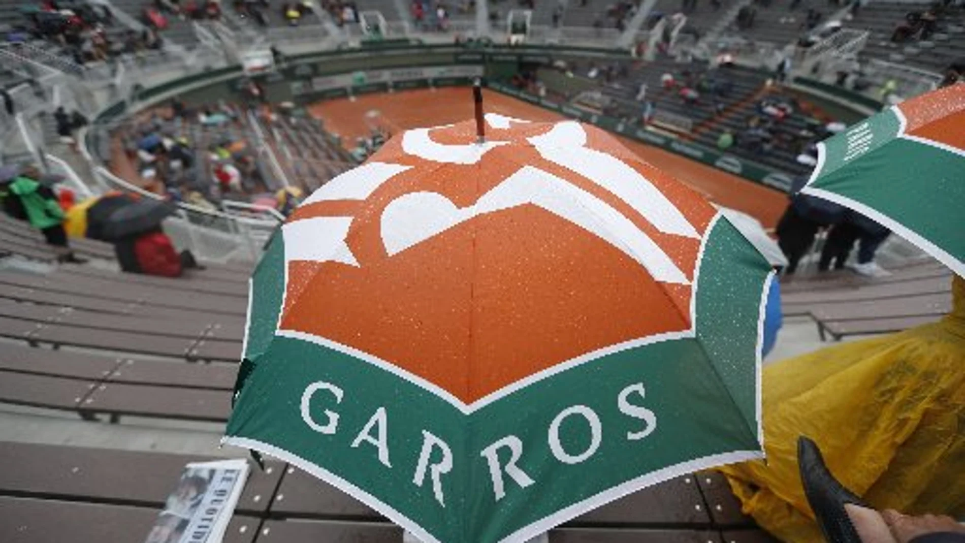 Un espectador protegiéndose con un paraguas de la lluvia en Roland Garros