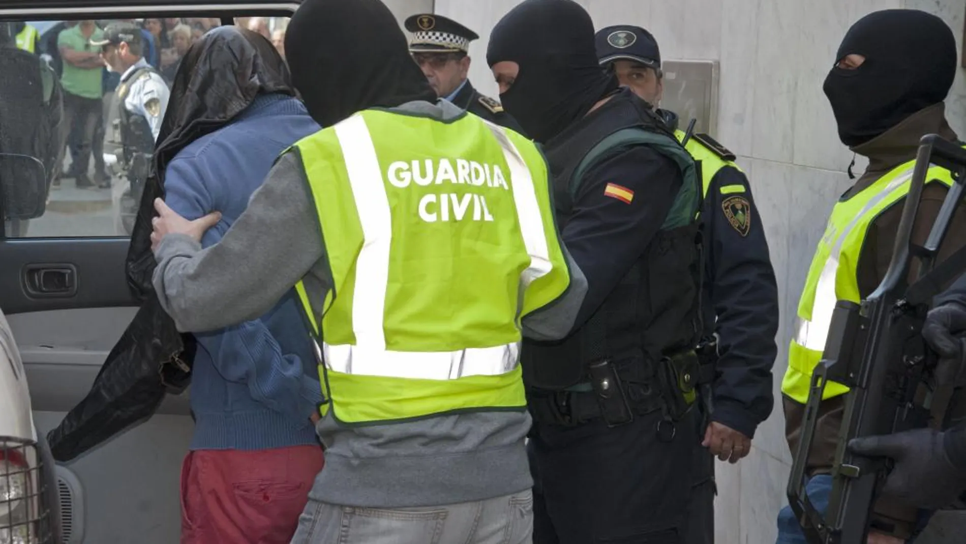 La Guardia Civil introduce en un coche al joven detenido hoy en Santa Coloma de Farners (Girona), un marroquí de 43 años, por financiación del grupo terrorista yihadista Dáesh