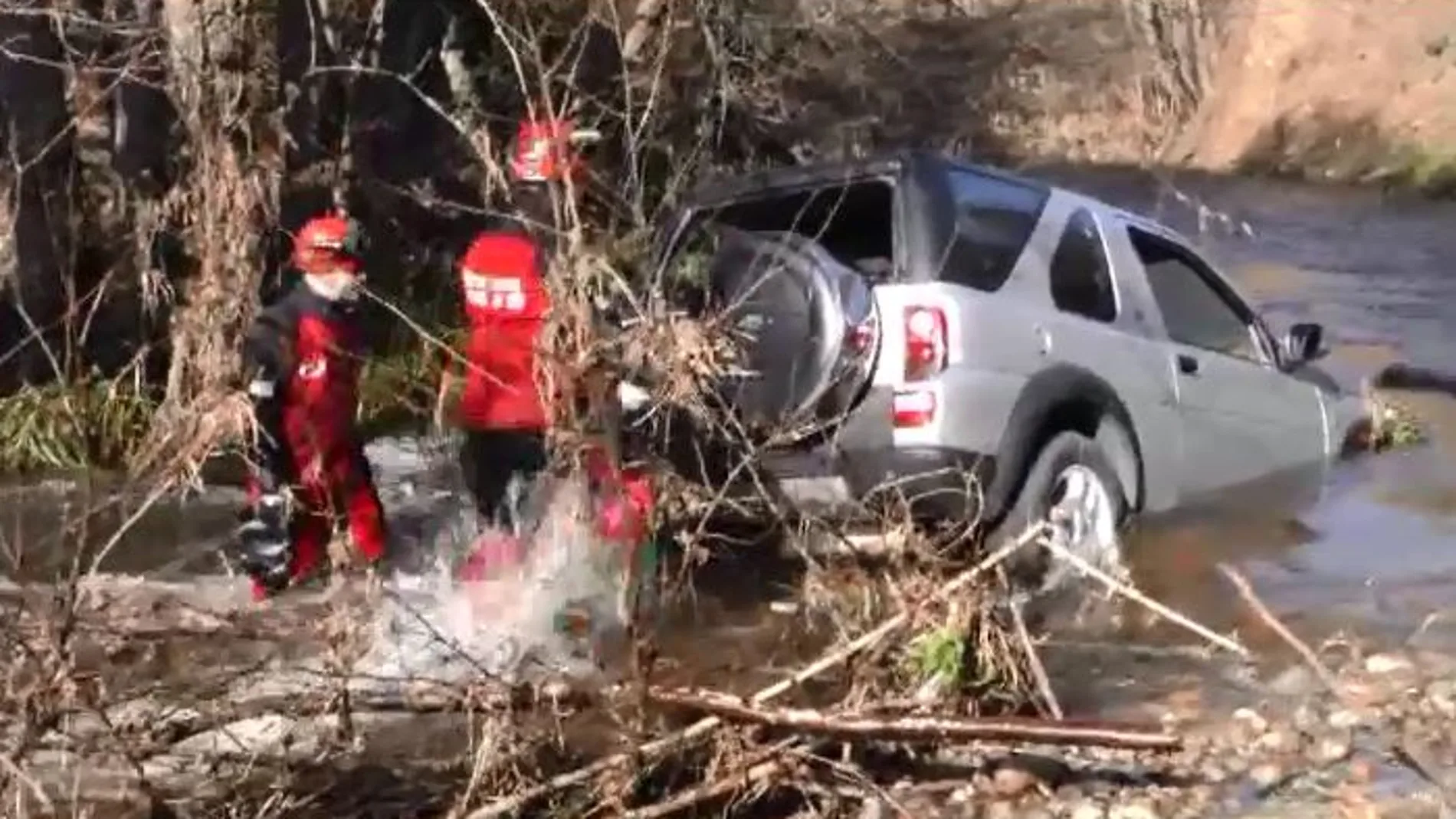 Dos bomberos cerca del vehículo en el que se encontraba la víctima