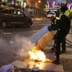 Policías municipales intentan apagar un contenedor incendiado en la calle Alcalá, junto a la Plaza de Cibeles