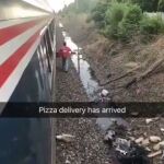 El repartidor caminando por la vía del tren para entregar la pizza