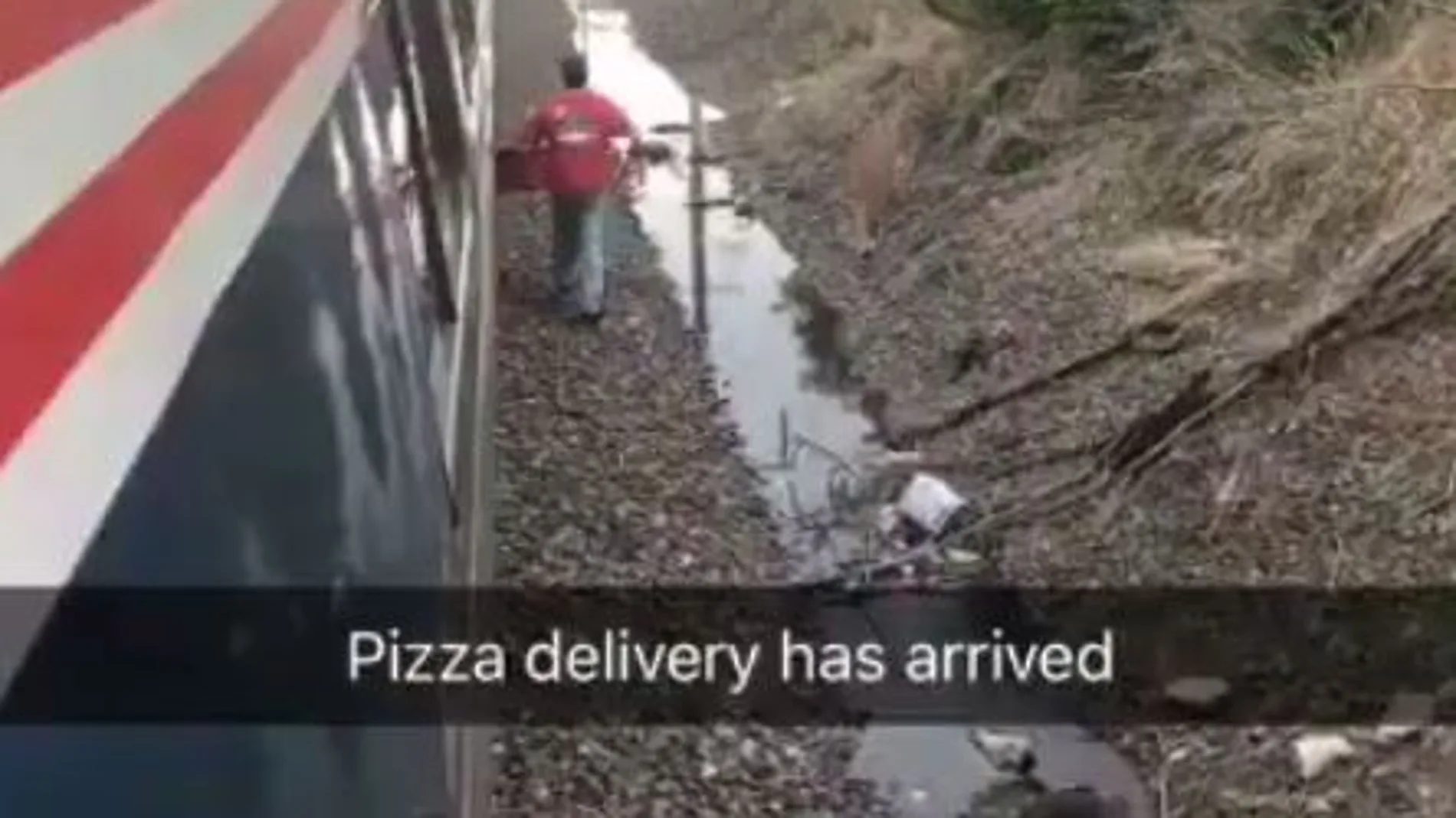 El repartidor caminando por la vía del tren para entregar la pizza