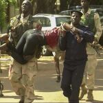 Personal militar de Mali traslada a una mujer herida a su salida del hotel de lujo Radisson Blu en Bamako