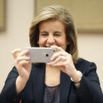 La ministra de Empleo, Fátima Báñez, hace una foto con su teléfono móvil a los fotógrafos, antes de su comparecencia en la Comisión de Empleo y Seguridad Social