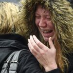 Una mujer se emociona mientras observa los ramos de flores mientras guarda un minuto de silencio en el Puente de Londres