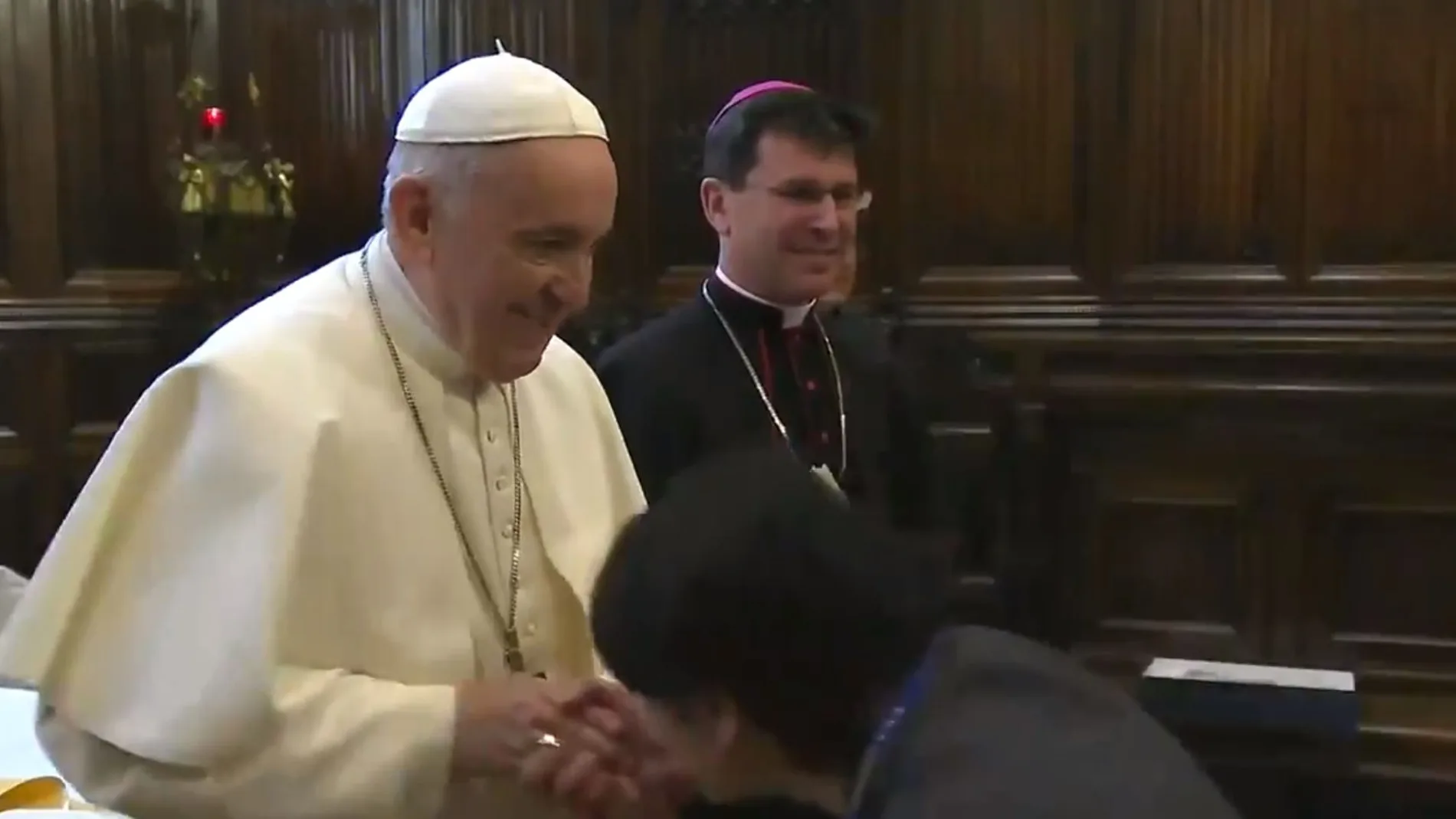 Momento en el que el Papa trata de retirar la mano ante el intento de un feligrés de besar el anillo