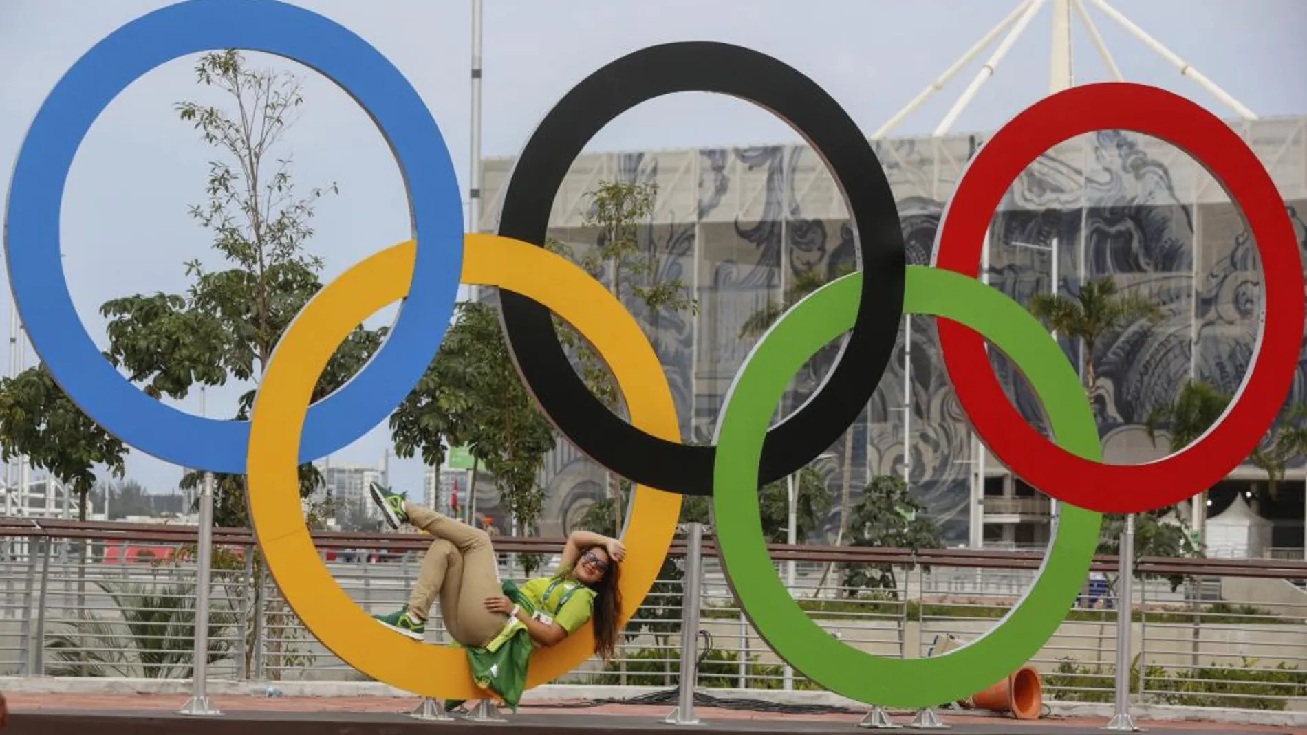 Una voluntaria descansa en los anillos olímpicos en la Villa Olímpica en Río de Janeiro (Brasil).